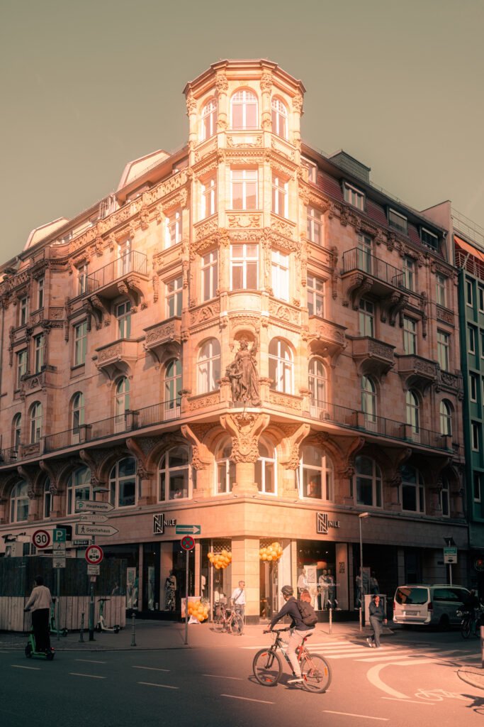 Ornamentreiches Jugendstil-Eckgebäude an der Frankfurter Hauptwache im warmen Abendlicht, mit Passanten und Fahrradfahrern im Vordergrund.Du hast gesagt: Kannst du mir noch weitere Ideen geben, das ist am Roßmarkt in Frankfurt entstanden